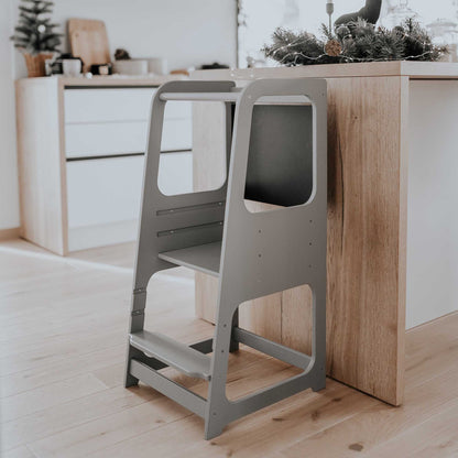 Grey Montessori step stool positioned next to the kitchen cabinet, enhancing accessibility and independence for little ones.