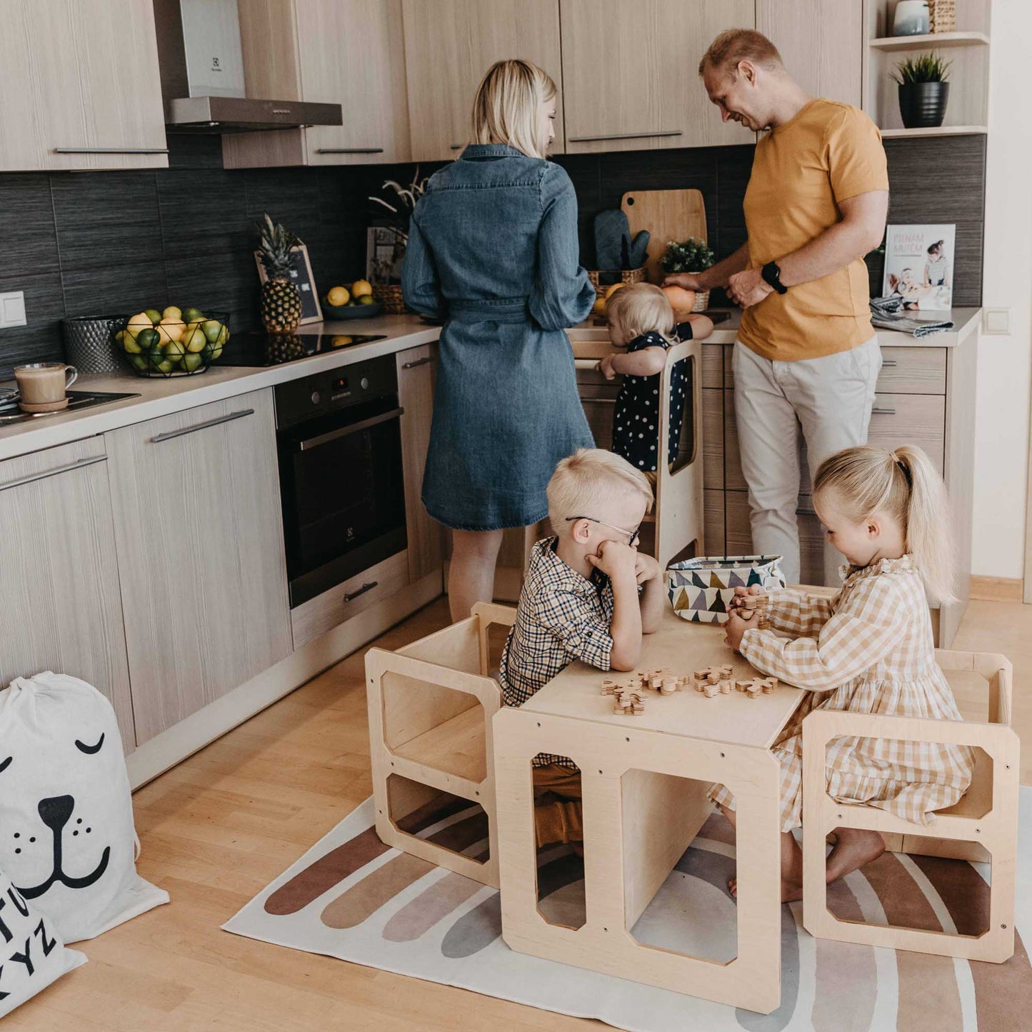 A family in a kitchen with a Sweet Home From Wood Montessori weaning table and 2 chair set.