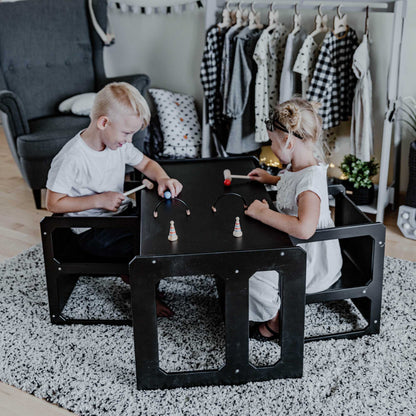 Two children playing at a Montessori weaning table and 2 chair set in a room.