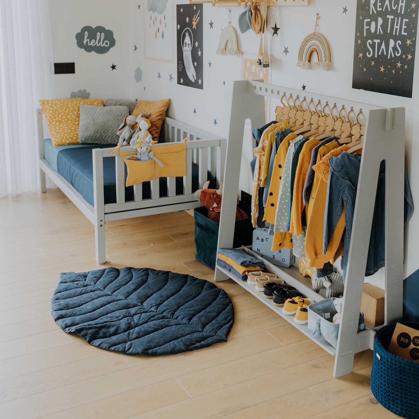 A Montessori-inspired boy's room with a Sweet Home From Wood kids' platform bed on legs with 3-sided rails, decorated in blue and yellow.