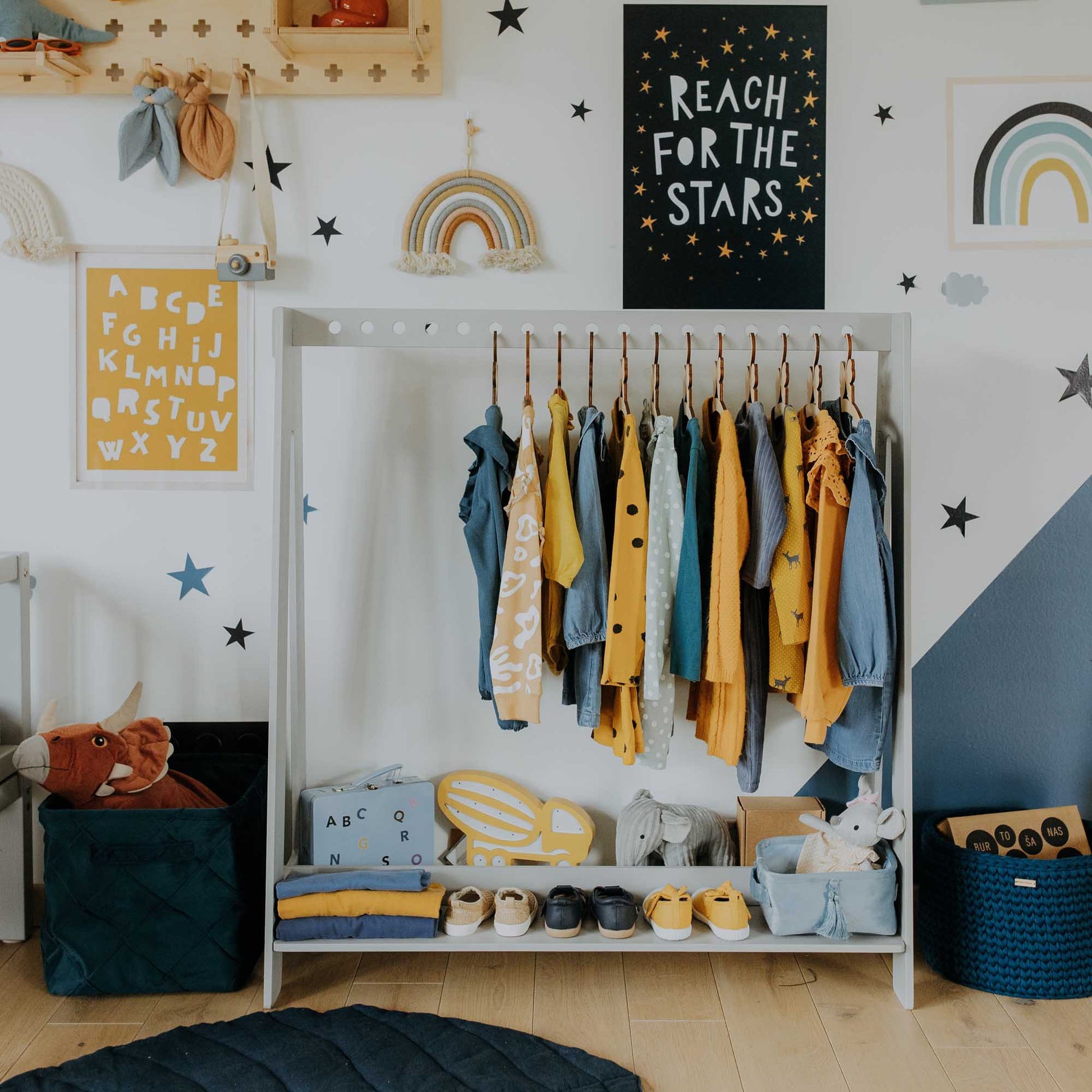 A child's room with an A-frame kids' clothing rack from Sweet Home From Wood, blue, yellow walls, and stars on the wall.
