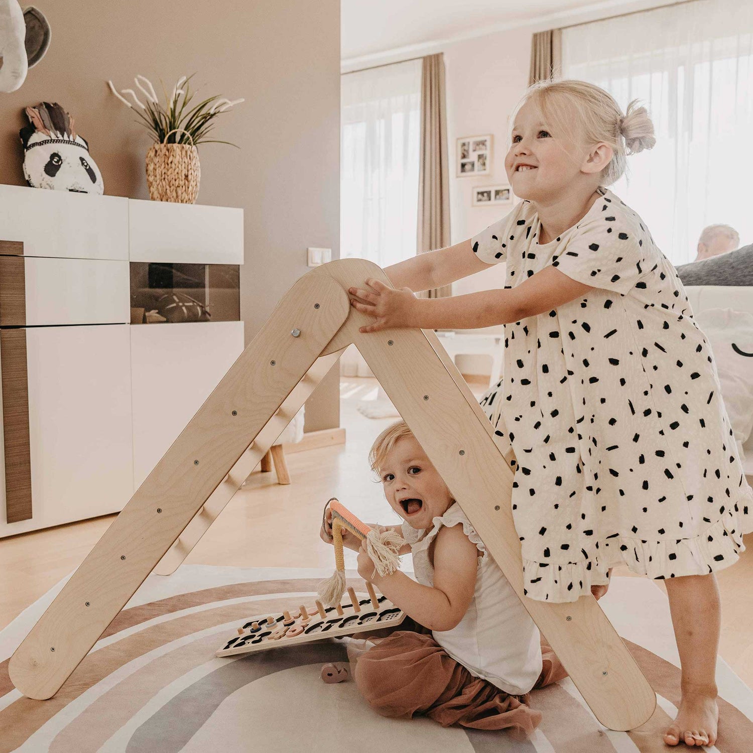 Two children playing with wooden toys in a living room.