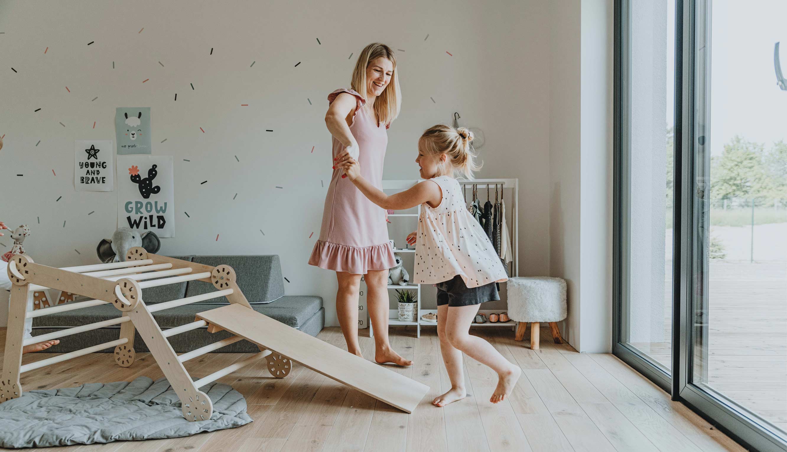 A mother and daughter playing with a wooden slide in a living room.