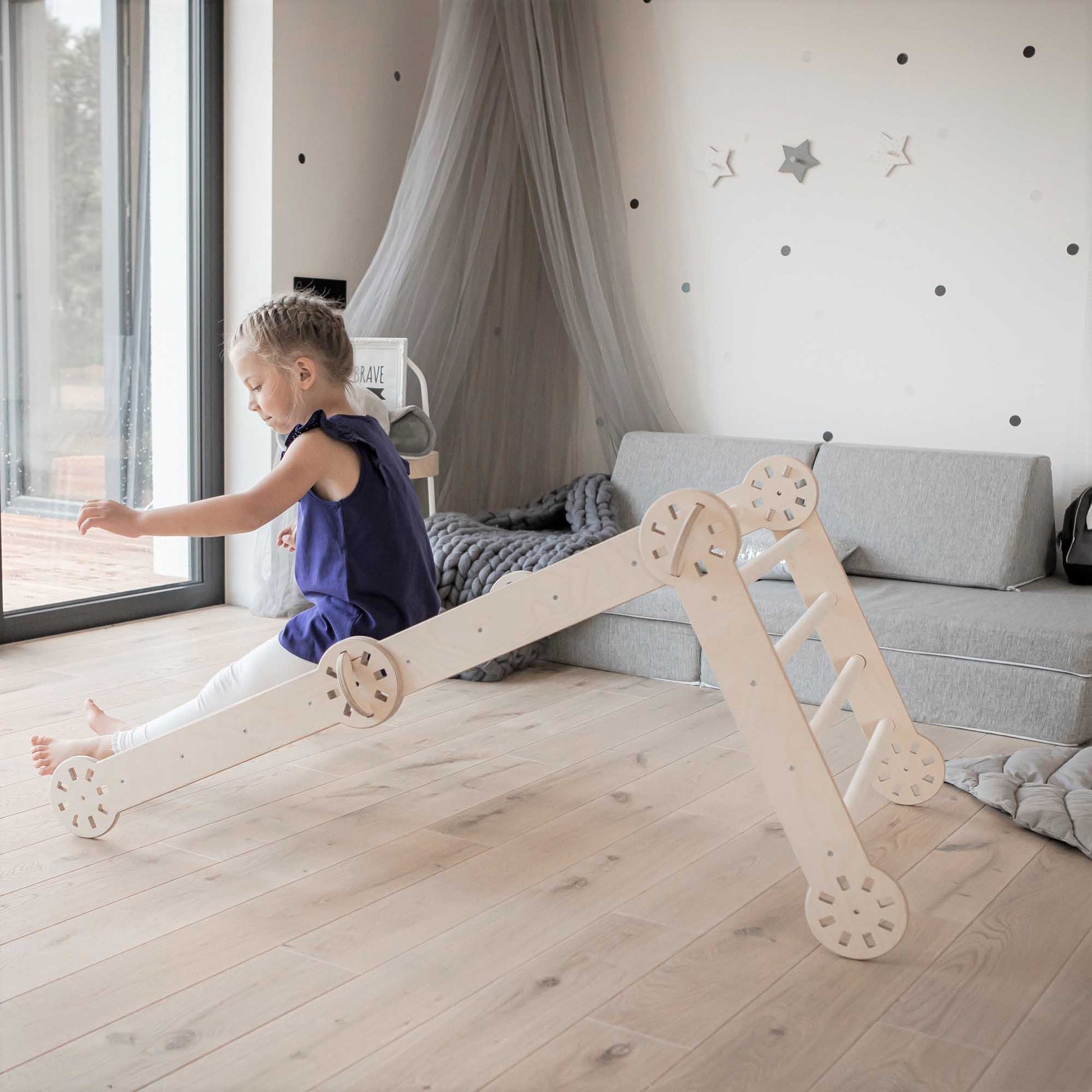 A child is playing with a wooden toy, a Transformable climbing gym, in a living room.