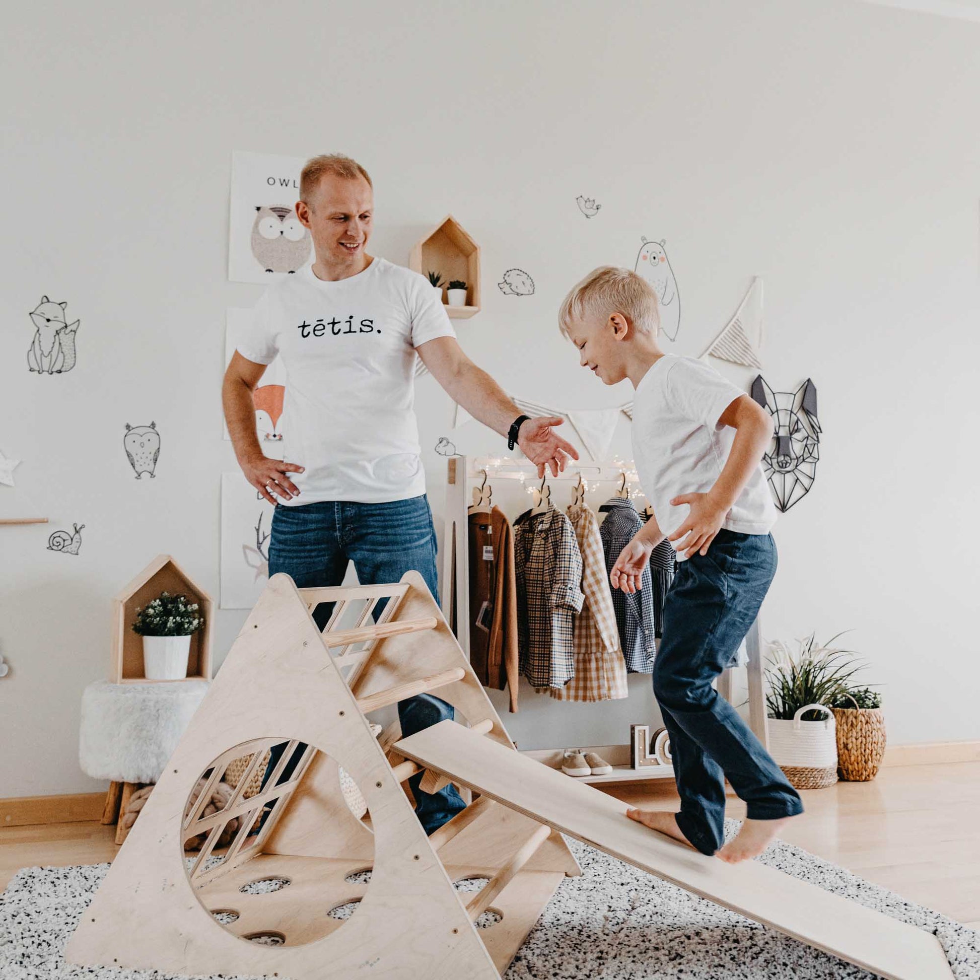 A man and his son enjoying Montessori-inspired wooden toys in a room, including a Climbing Triangle + Climbing Arch + a ramp.