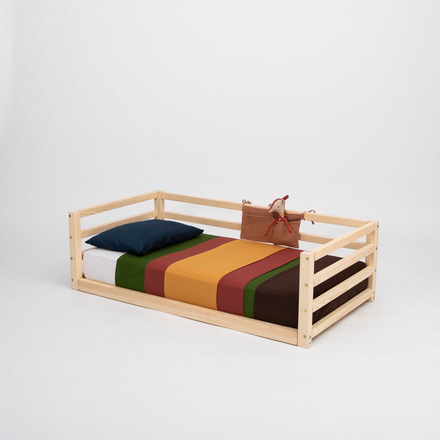 A Sweet Home From Wood children's floor level bed with 3-sided safety rail featuring colorful stripes and wooden slats.