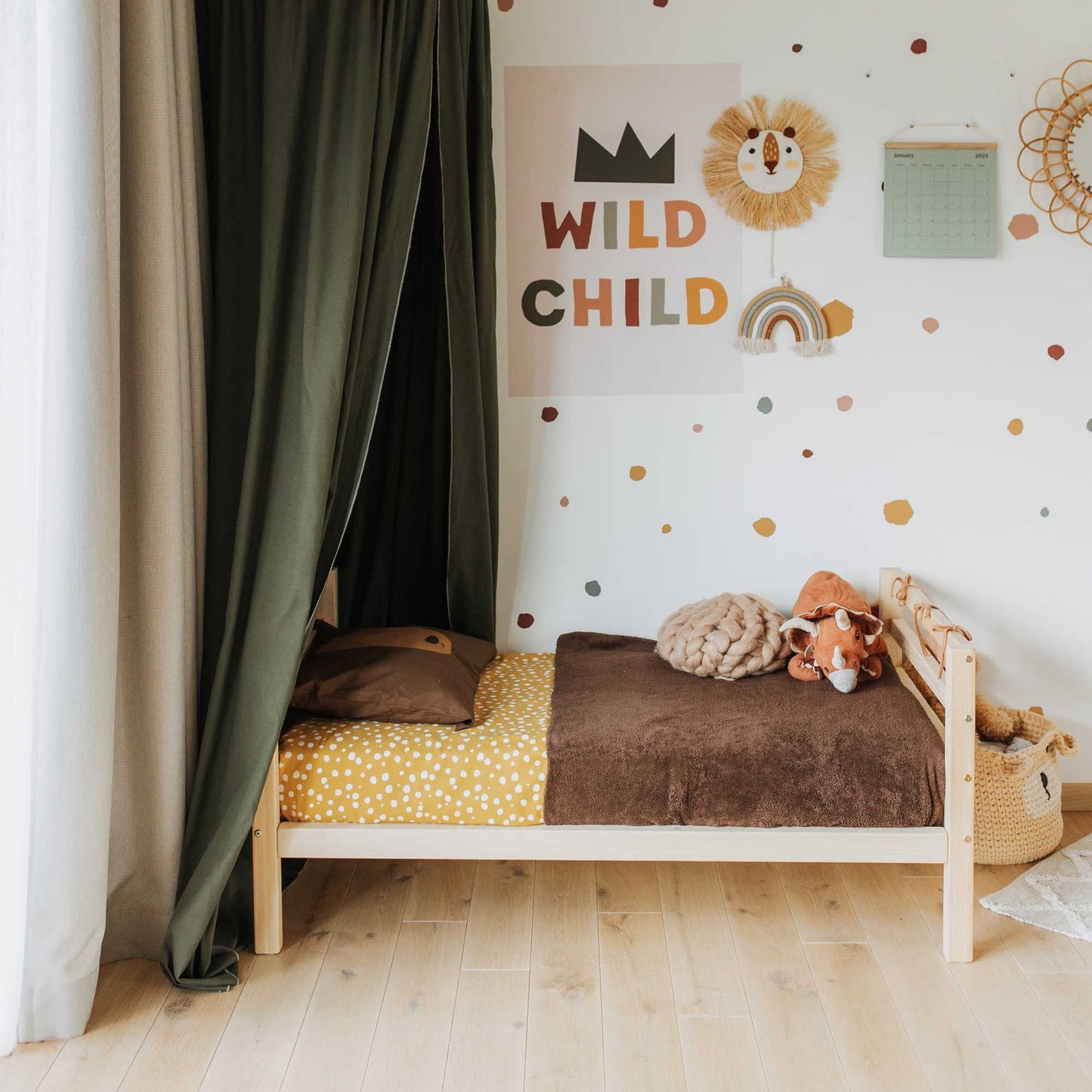 A child's room with a Sweet Home From Wood 2-in-1 kids' bed with a horizontal rail headboard and footboard that is long-lasting and grows with the child, surrounded by teddy bears.