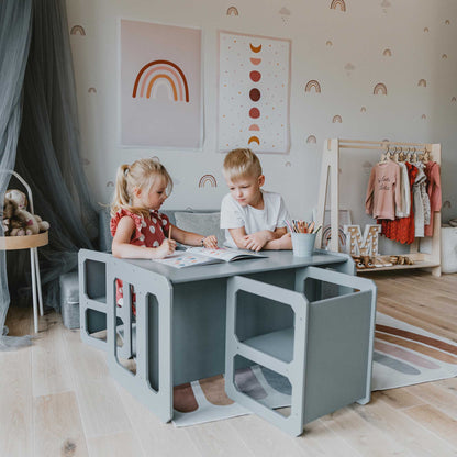 Two children sitting at a Sweet Home From Wood Montessori weaning table and 2 chair set in a child's room.