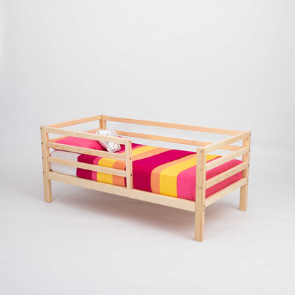 A 2-in-1 transformable kids' bed with a pink and yellow striped blanket from Sweet Home From Wood.