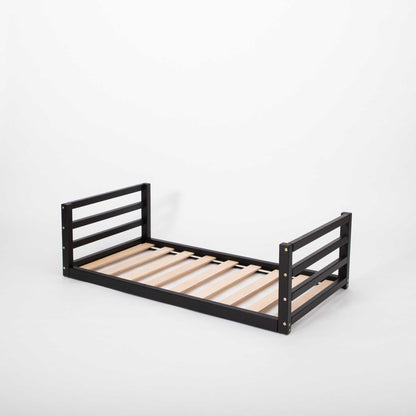 A black Sweet Home From Wood toddler floor bed, with a solid pine or birch wood frame and wooden slats.