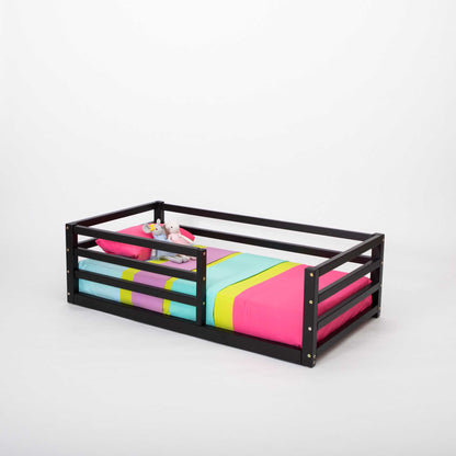 A transitional Sweet Home From Wood black toddler bed with a colorful bed sheet ideal for independent sleeping.