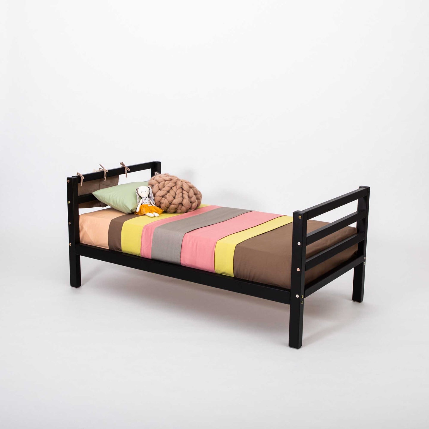 A long-lasting 2-in-1 kids' bed with a black frame and colorful bedding that grows with the child from Sweet Home From Wood.