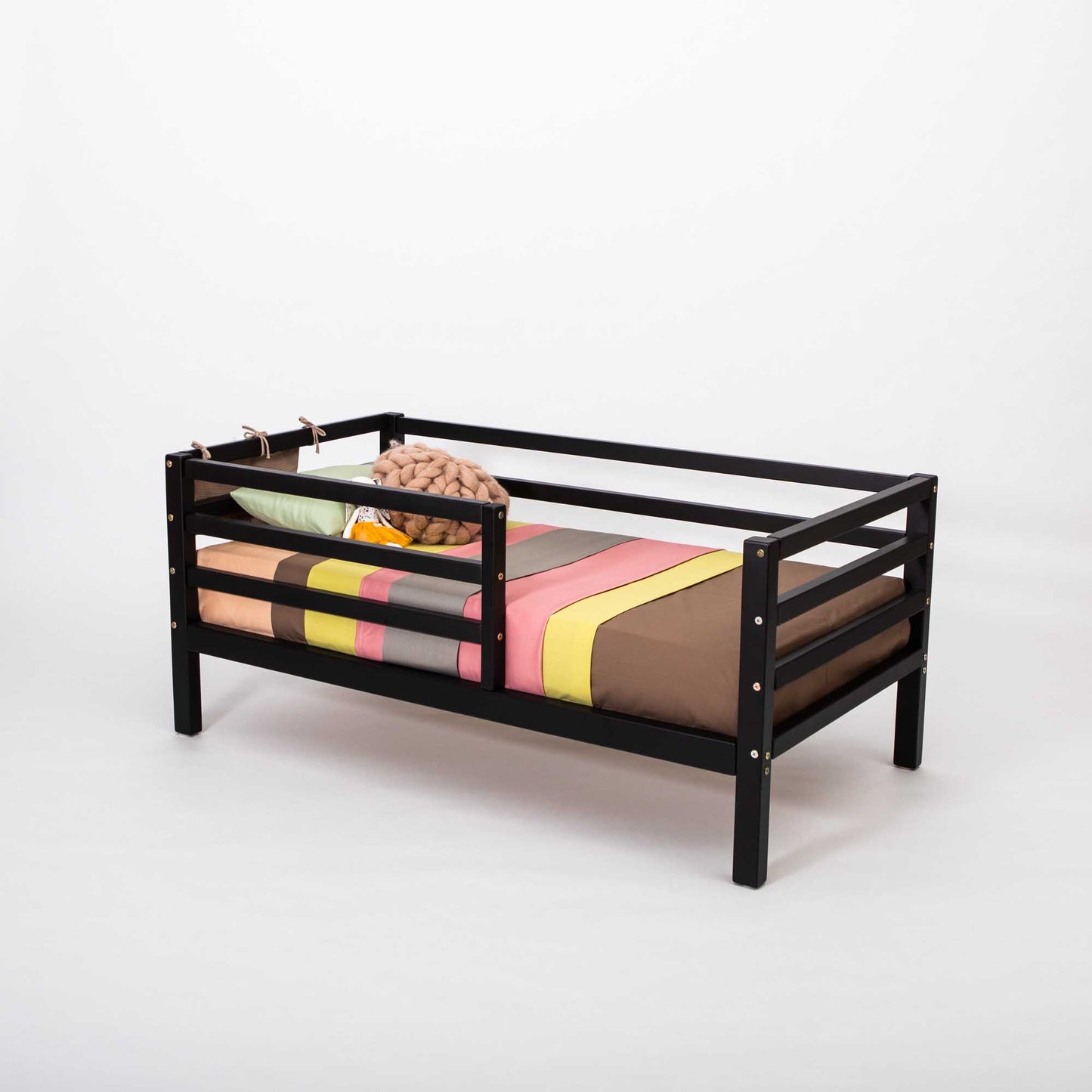 A Sweet Home From Wood Kids' bed on legs with a horizontal rail fence and a colorful bed sheet.